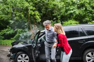 A woman helping a man get out of the car after an accident